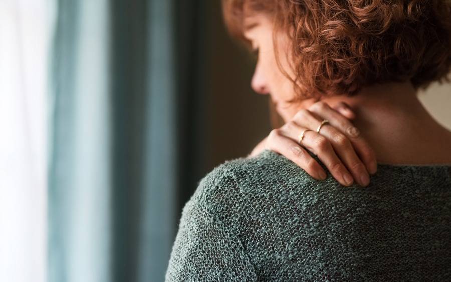 A woman experiences frozen shoulder pain.