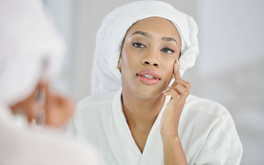 A woman looking at mirror after a thread face lift.