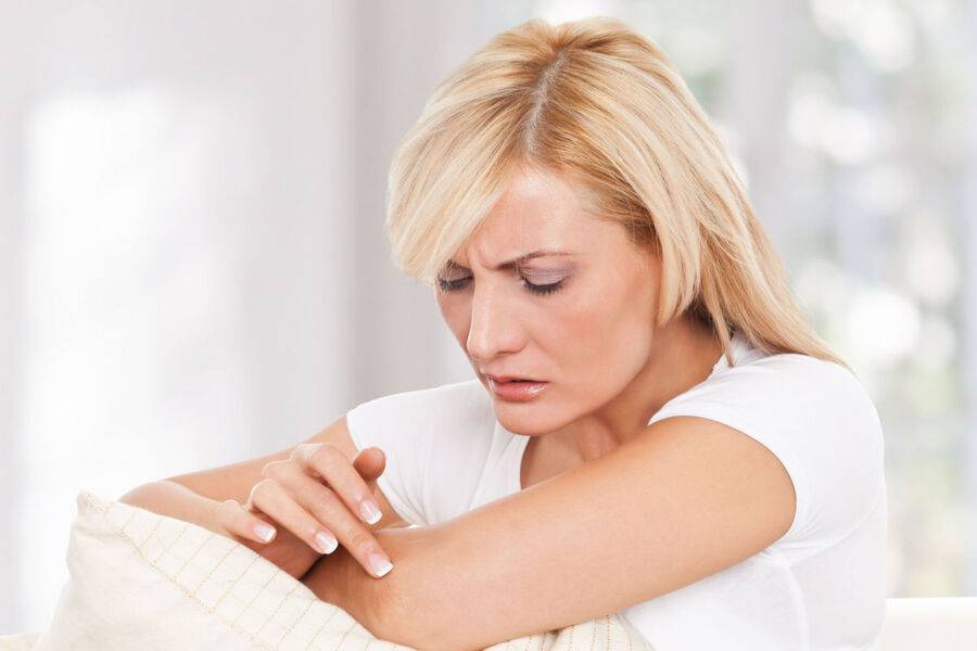 A woman looks at a white spot on her skin, could be eczema.