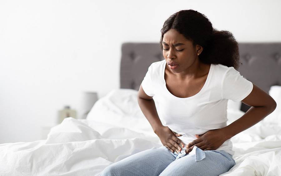 A woman grabs her stomach in pain as a result of endometriosis.
