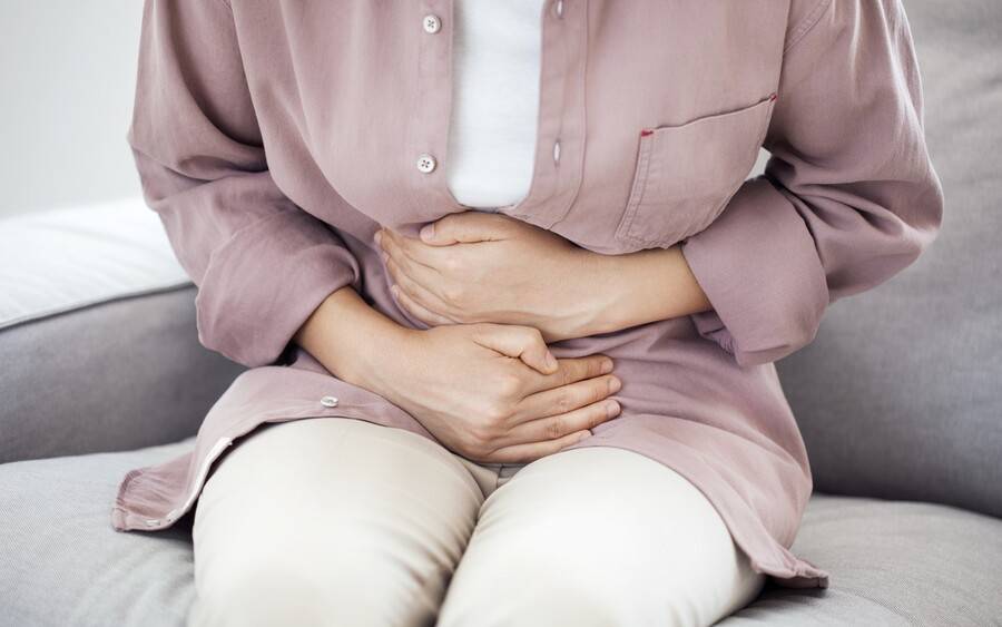 Woman holds her tummy, maybe with a gallbladder health issue.