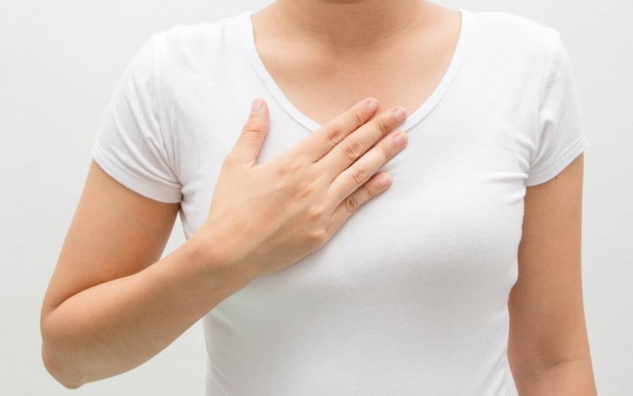 Woman grabs her chest wondering if she has heartburn or GERD.