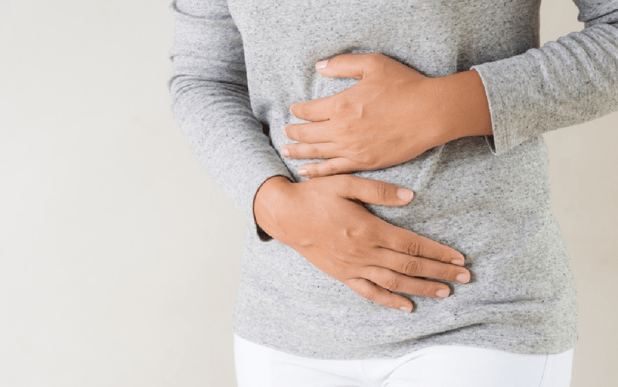 A woman with irritable bowel syndrome holds her stomach in pain.