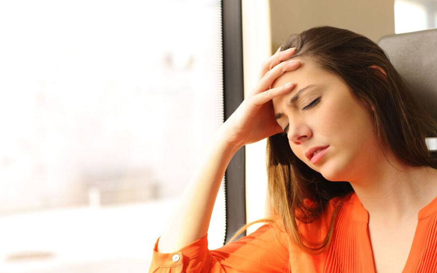 A woman experiencing dizziness, a sign of vertigo.