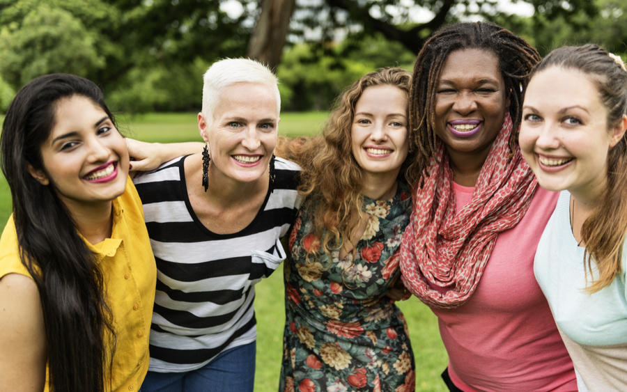 A group of smiling women put their arms around each other in support.