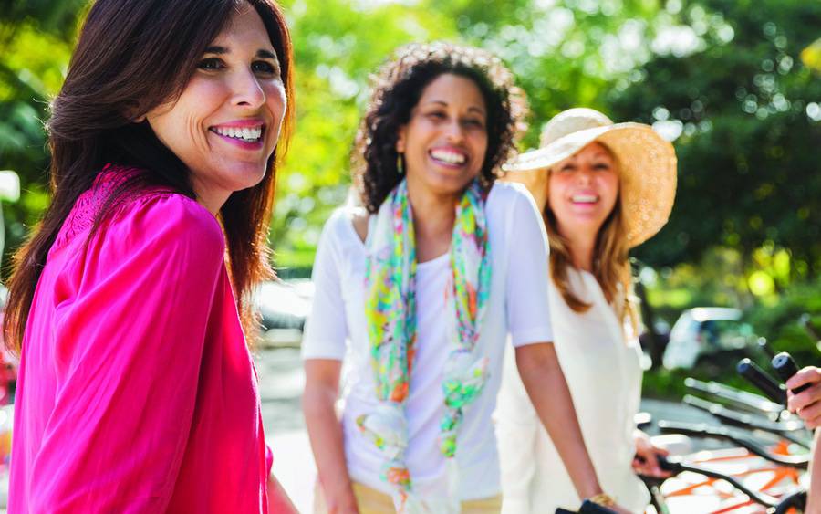 A group of women looking well and smiling as they are outside exercising together.