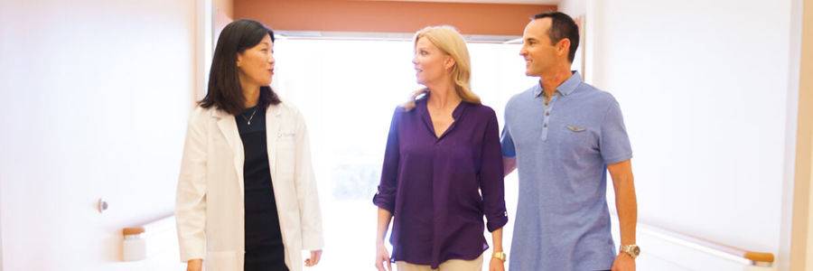 A Scripps doctor walks down a hospital hallway with a couple, representing the highly specialized doctors and care at Scripps.