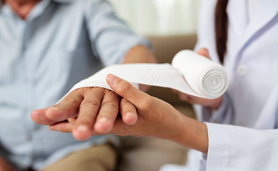 A wound therapy specialist provides treatment to a patient with a hand injury.