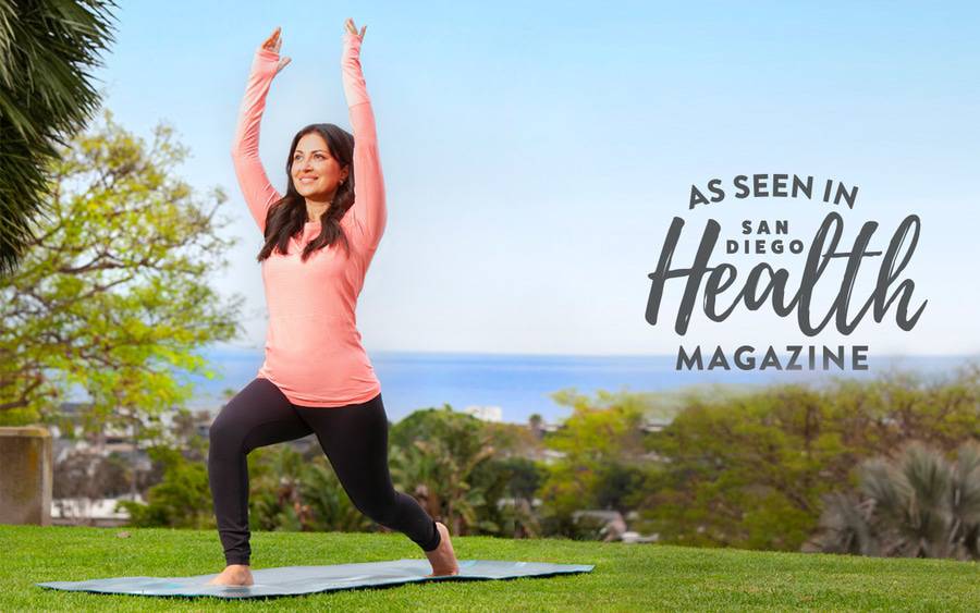 Kosha Nathwani, MD, a Scripps Clinic family medicine physician, is in a warrior 1 yoga pose with the ocean in the background.