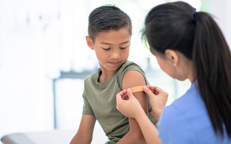 A young boy in a doctor's office is receiving a flu shot, illustrating the importance of getting a flu vaccination.