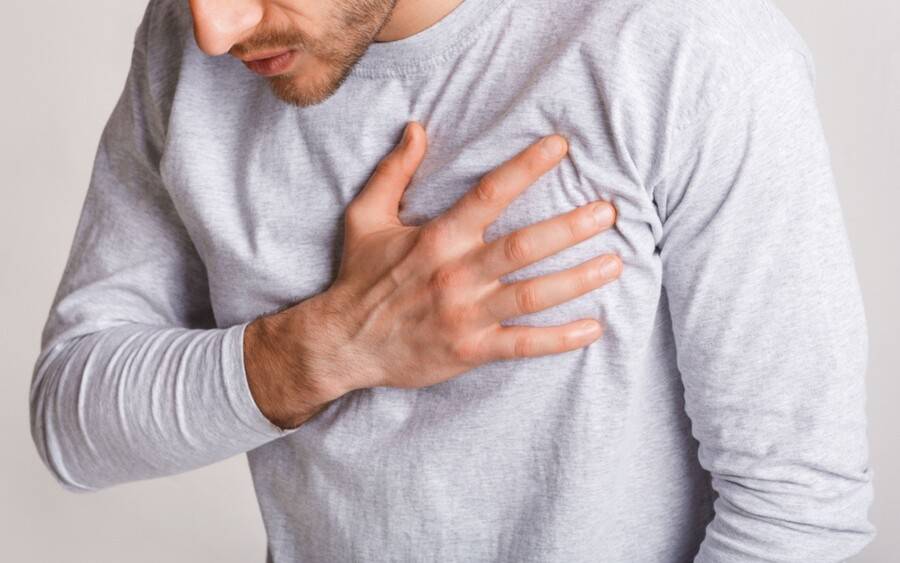 A young man grabs his chest as if he were experiencing a heart attack.