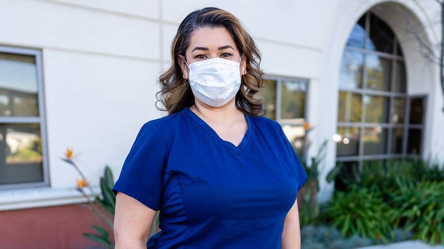 Yvonne Meneses, RN standing outside in a facemask and blue scrubs, one of the eight Scripps Nurses of the Year 2020.