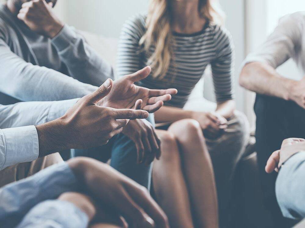 A man talks to a support group, representing people with aphasia practicing their communication skills in a supportive environment. 