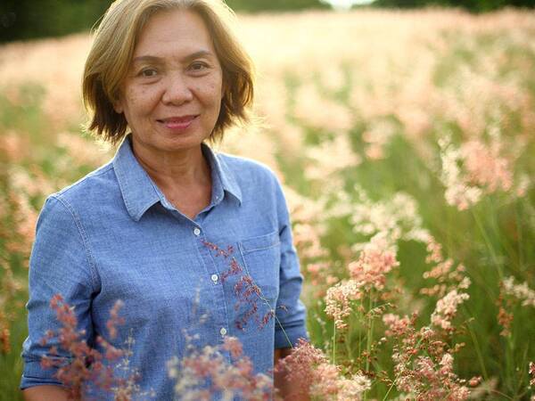An older woman standing in a field of flowers