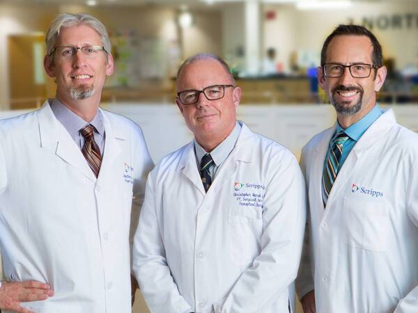 Three physicians wearing white lab coats 