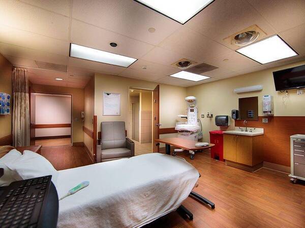 Hospital room with a bed, reclining chair, bassinet and sink at Scripps Mercy San Diego