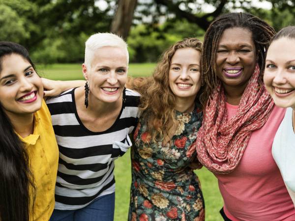 A group of smiling women with heart conditions put their arms around each other in support.