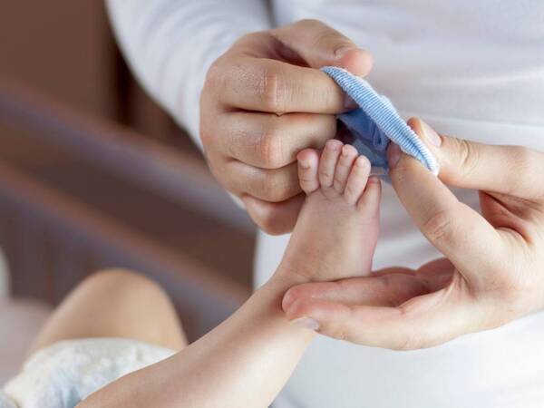 A parent prepares to slide a sock onto a tiny newborn foot.