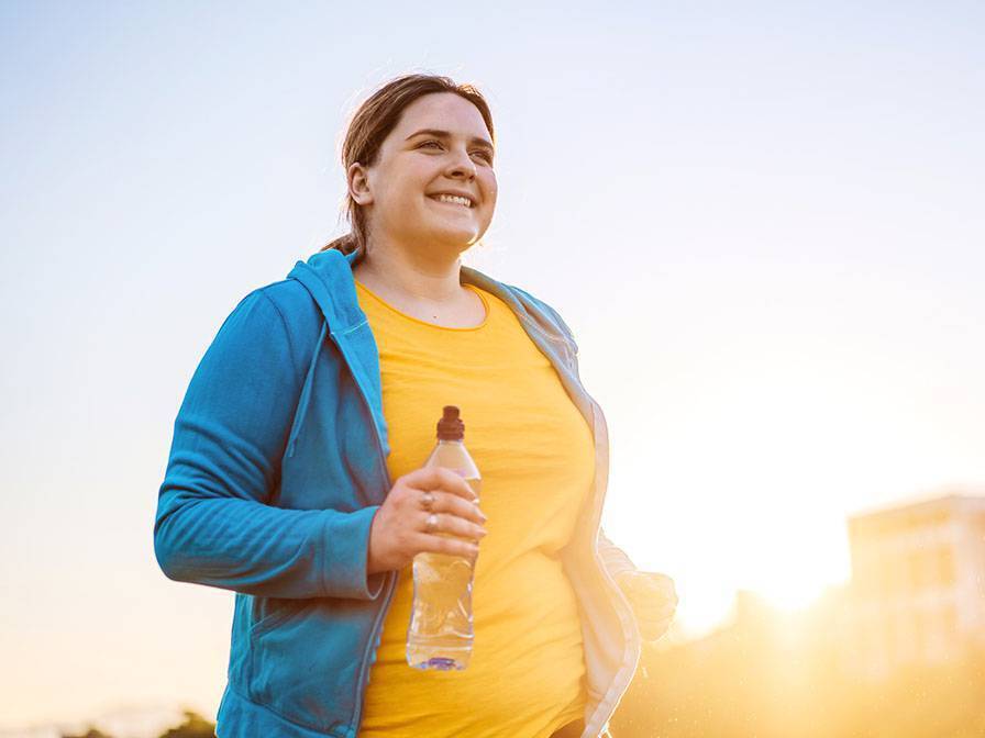 A young woman jogs in the early morning sunlight.
