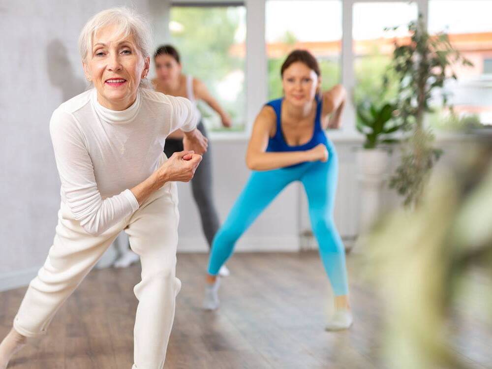 Senior woman participates in a Zumba Gold exercise class.