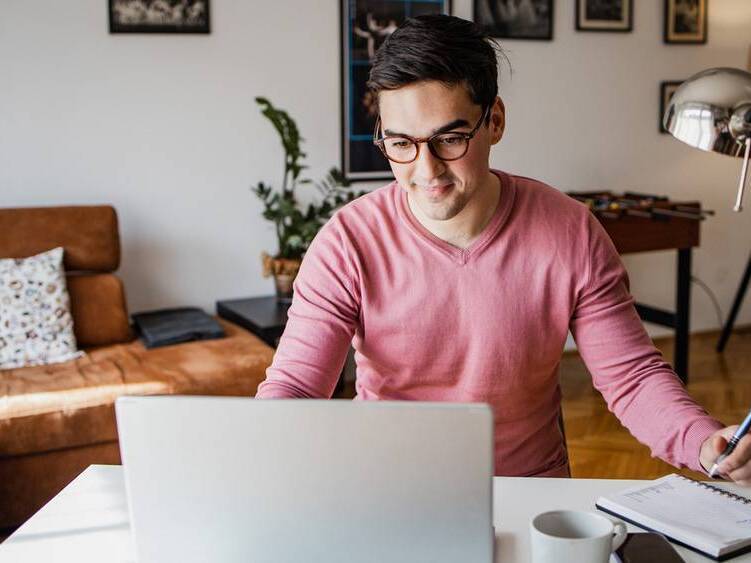 A young man in glasses looking at a laptop computer.