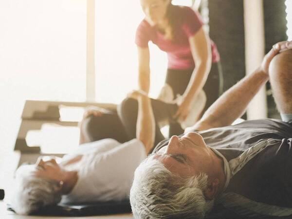 A senior man and woman participate in an exercise class designed to strengthen the pelvic floor.