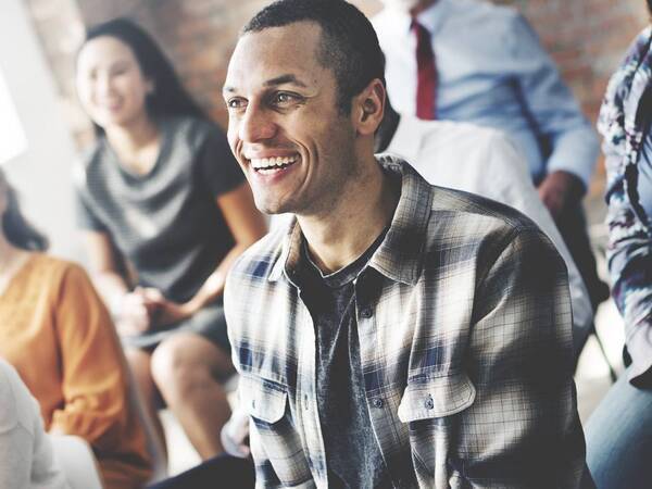 A young man smiles as he participates in a support group for kidney disease.
