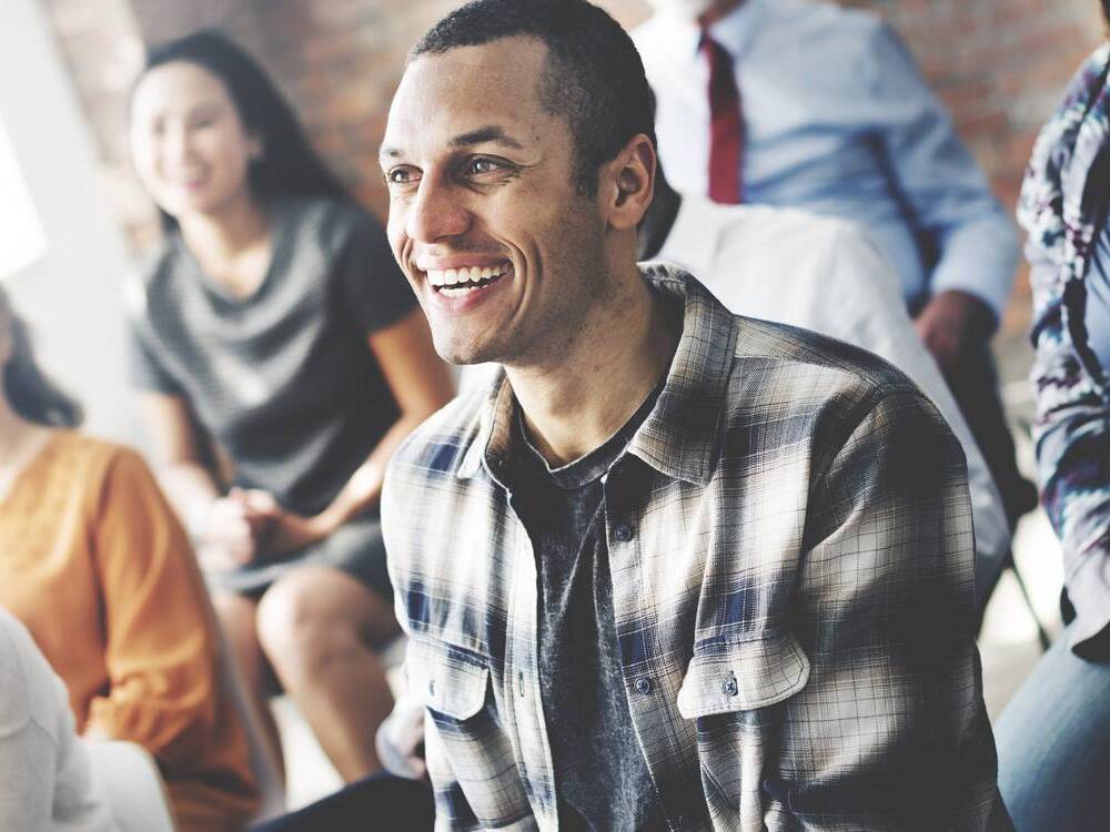 A young man smiles as he participates in a support group for kidney disease.