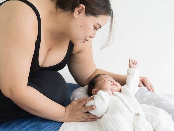 A new mother sits on the floor to take care of her baby.