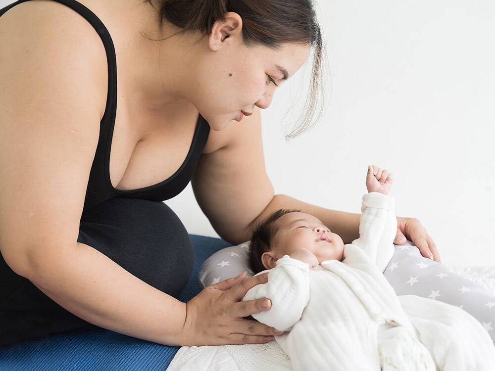 A new mother sits on the floor to take care of her baby.
