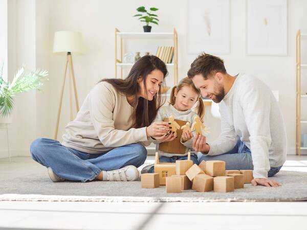 A young couple and their daughter play on the floor with blocks.