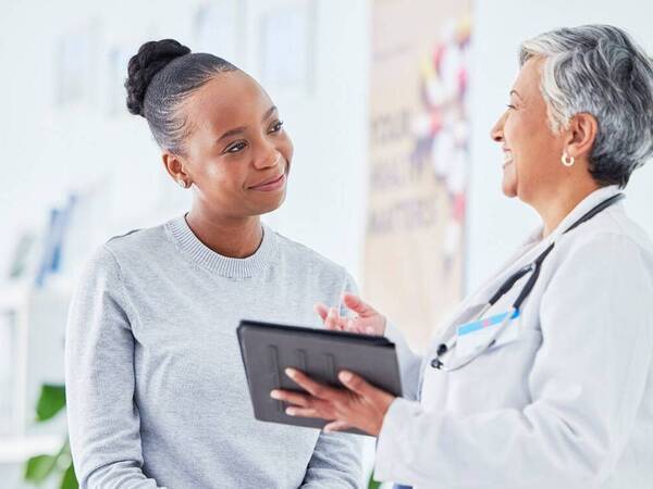 A young black woman smiles as she consults with her doctor.
