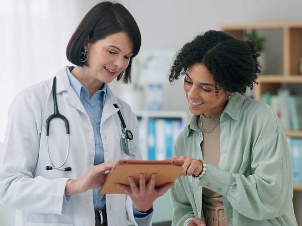 A female doctor reviews a treatment plan with a female patient. 