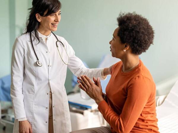 A female patient with a female provider in a clinical setting.