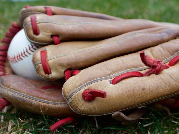 Baseball glove and baseball lying on the grass; baseball is among the sports for which athletes might jeopardize their health by taking performance enhancing supplements. 