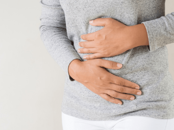 A woman with irritable bowel syndrome holds her stomach in discomfort.