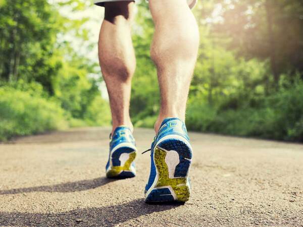 Close up image of man running on a trail in an outdoor setting 