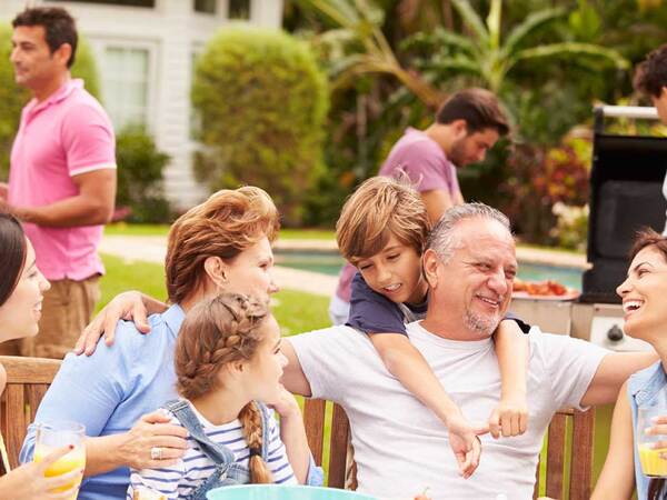 A large family dinner gathering in a San Diego backyard, with a swimming pool and barbecue visible in the background