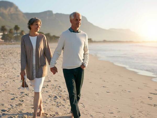 A mature couple walking on the beach.