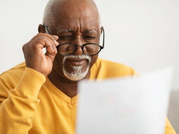 An older man uses glasses to read up close. He has presbyopia, also known as age-related farsightedness.