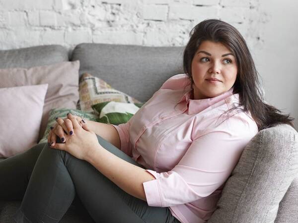A Hispanic woman sits, thinking and considering bariatric surgery.
