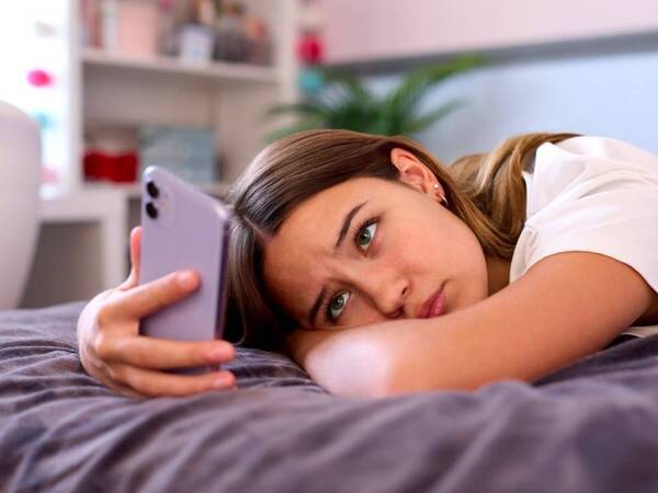A teen girl with depression stares at her iphone.