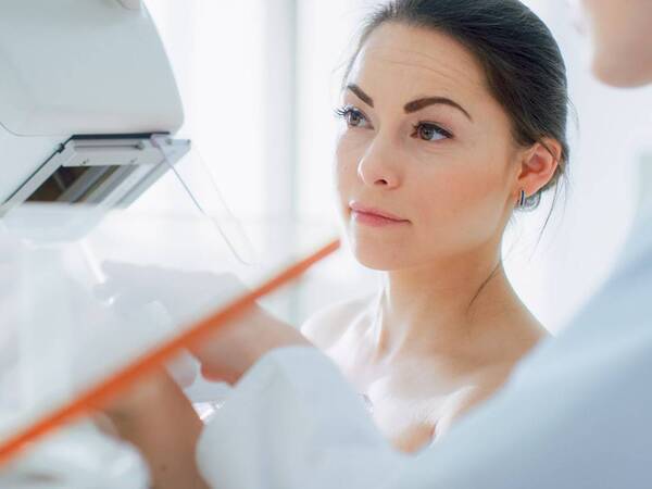 A young woman with previous breast surgery about to get a mammogram