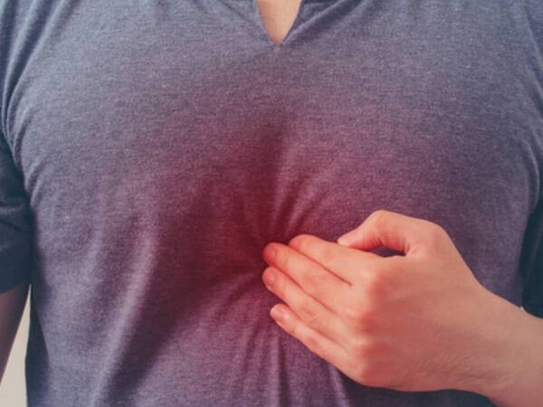 A man holds his chest while experiencing heartburn.