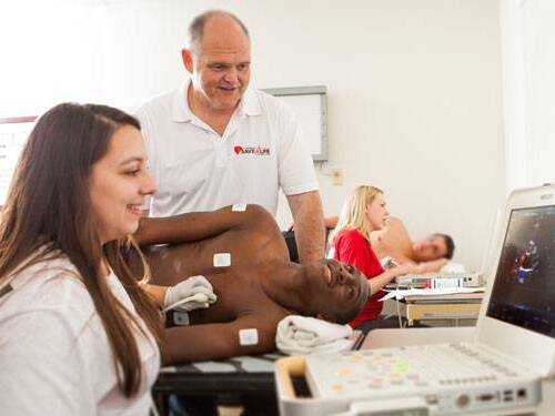 Providers giving a young athlete a heart diagnostic test.