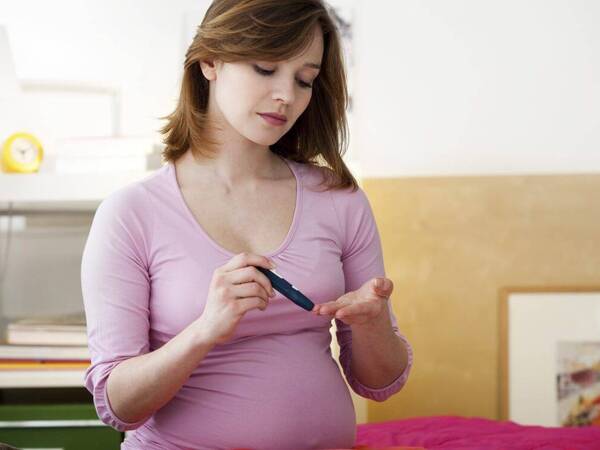 A pregnant woman with diabetes tests her blood sugar level.