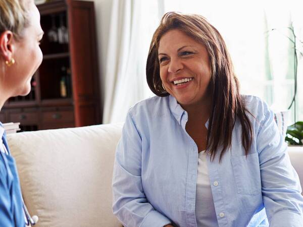 A physician discusses a diet plan with her prediabetes patient, a Hispanic woman who is smiling because she knows she can prevent type 2 diabetes from occurring.
