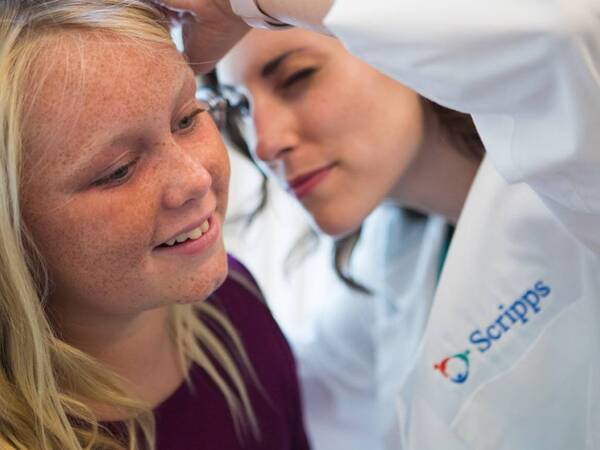 A Scripps HealthExpress Carmel Valley provider checks the ear of a young patient.