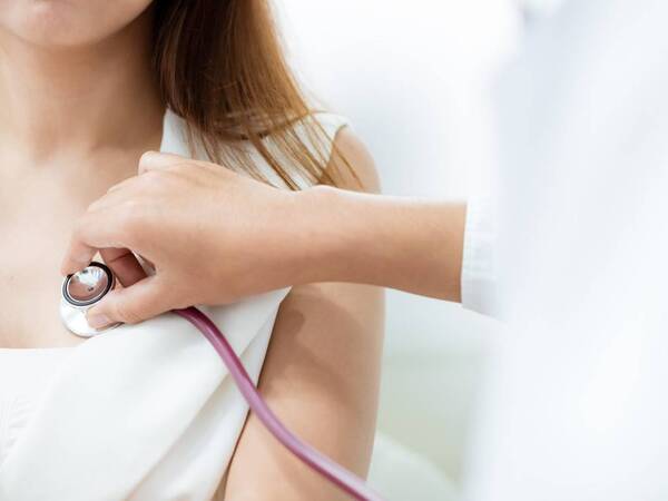 A physician checks a female patient's heartbeat using a stethoscope. She's checking for a heart murmur and possibility she may have atrial fibrillation.