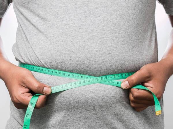 An overweight man measures his waist to see if he is by BMI definition obese.